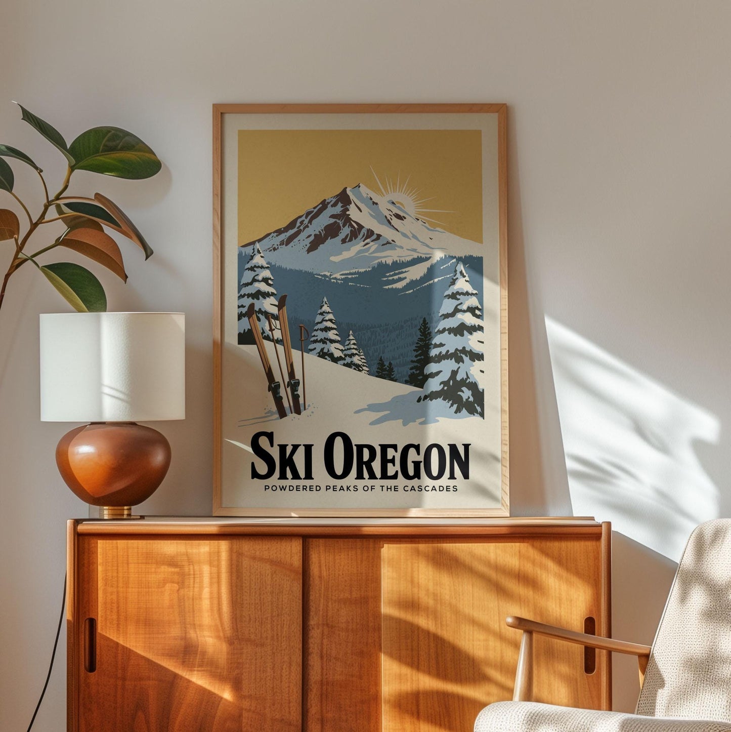 A framed poster of a snowy mountain landscape with ski equipment is displayed on a wooden cabinet in a room with a lamp and a plant.