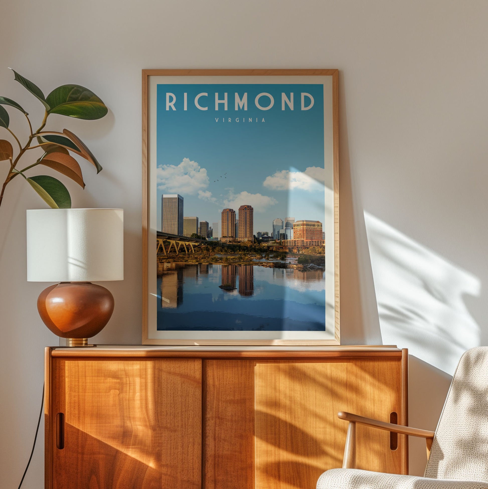 a framed poster of the Richmond, Virginia skyline, with a wooden cabinet and a lamp in the foreground.