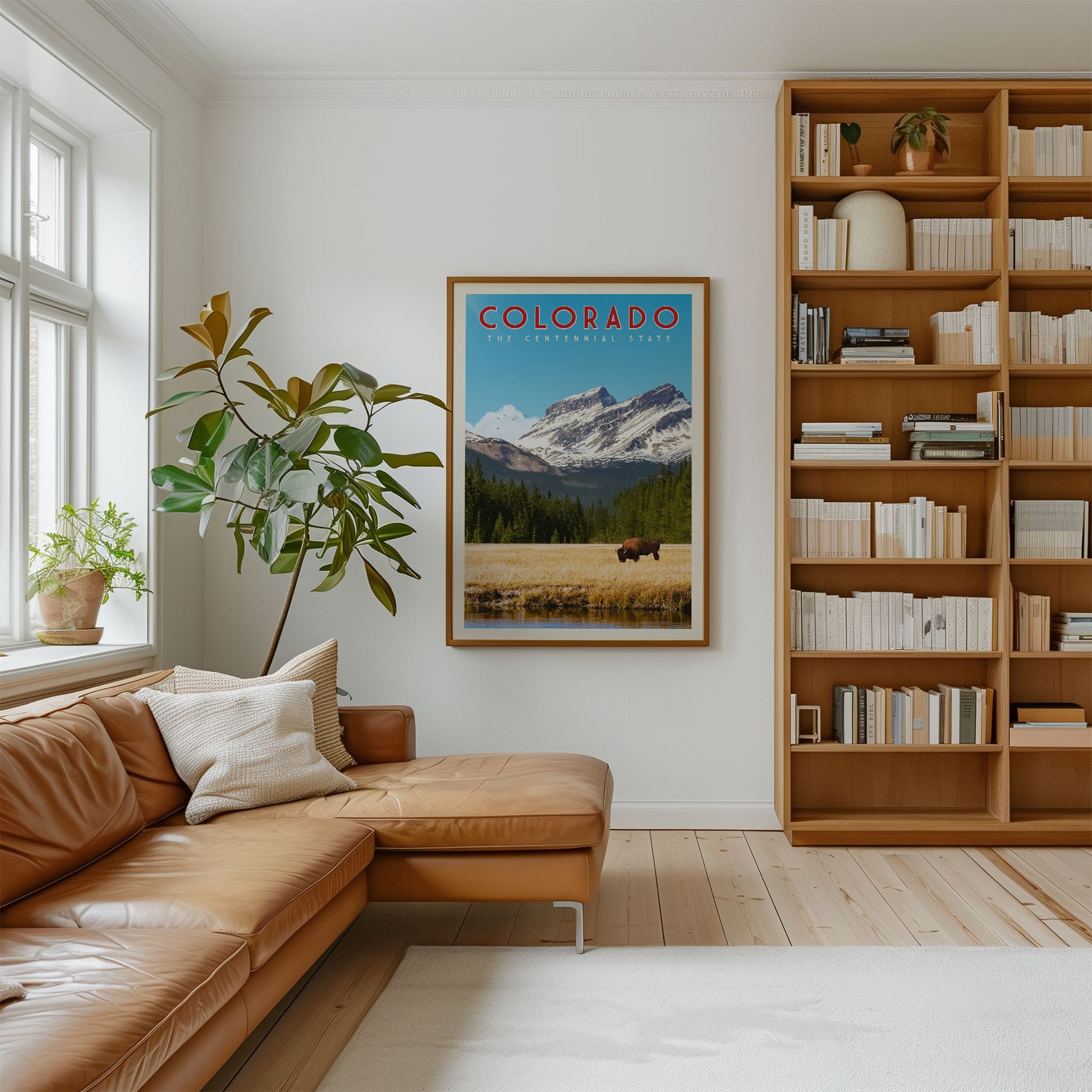 a cozy living room with a large bookshelf filled with books, a comfortable leather couch, and a framed poster of a scenic mountain landscape hanging on the wall.