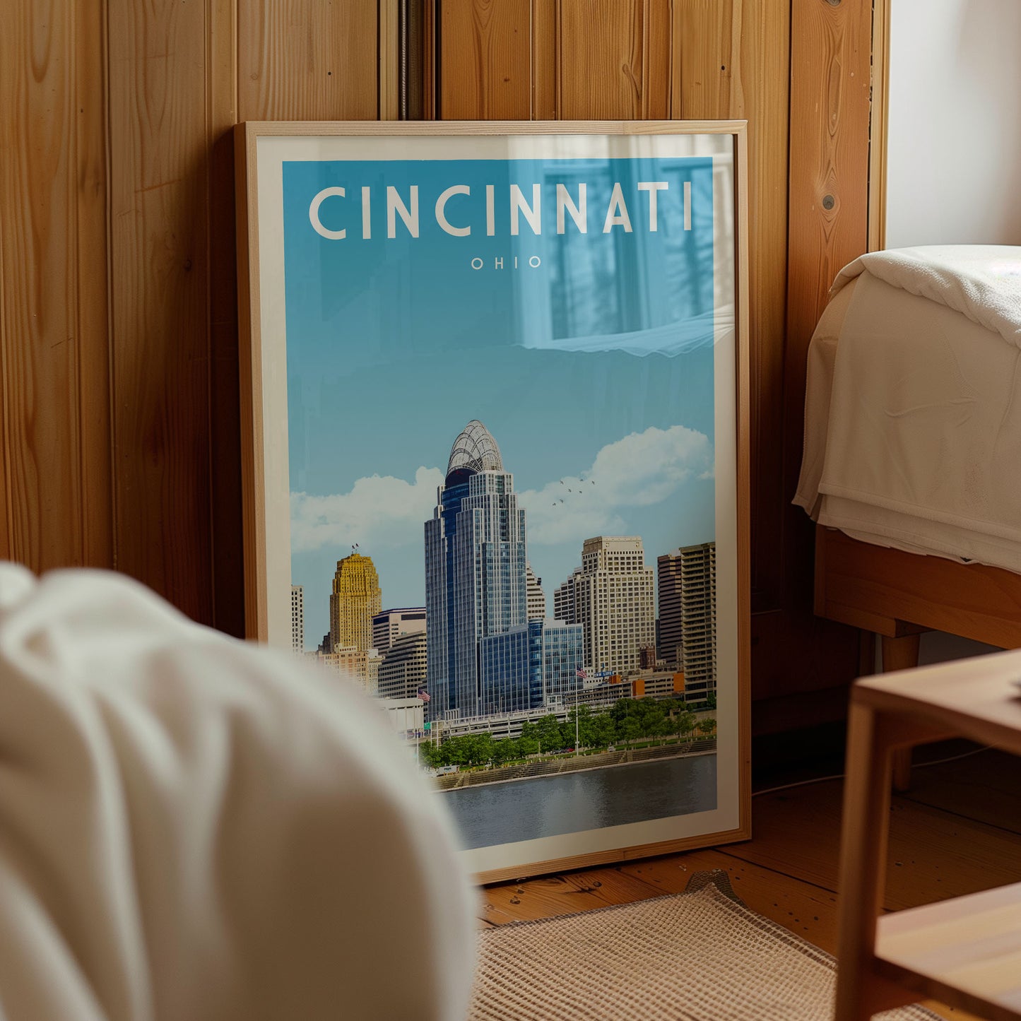 A framed poster of the Cincinnati skyline is displayed in a room with wooden paneling.