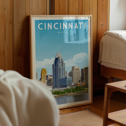 A framed poster of the Cincinnati skyline is displayed in a room with wooden paneling.