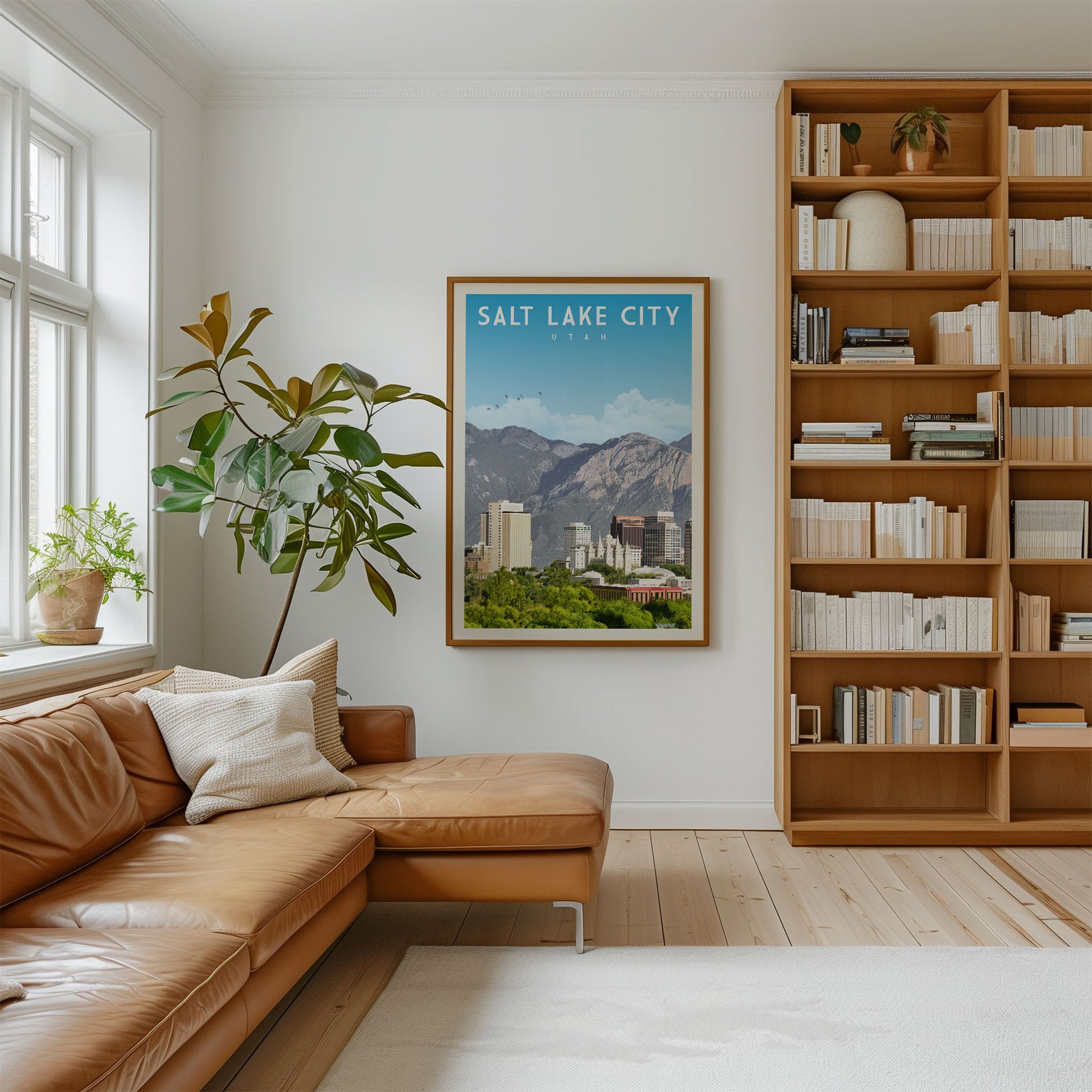 a cozy living room with a large window, a comfortable leather couch, a bookshelf filled with books, and a framed poster of Salt Lake City, Utah, hanging on the wall.