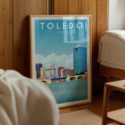A framed poster of the city of Toledo, Ohio, featuring a skyline with tall buildings and a river in the foreground.