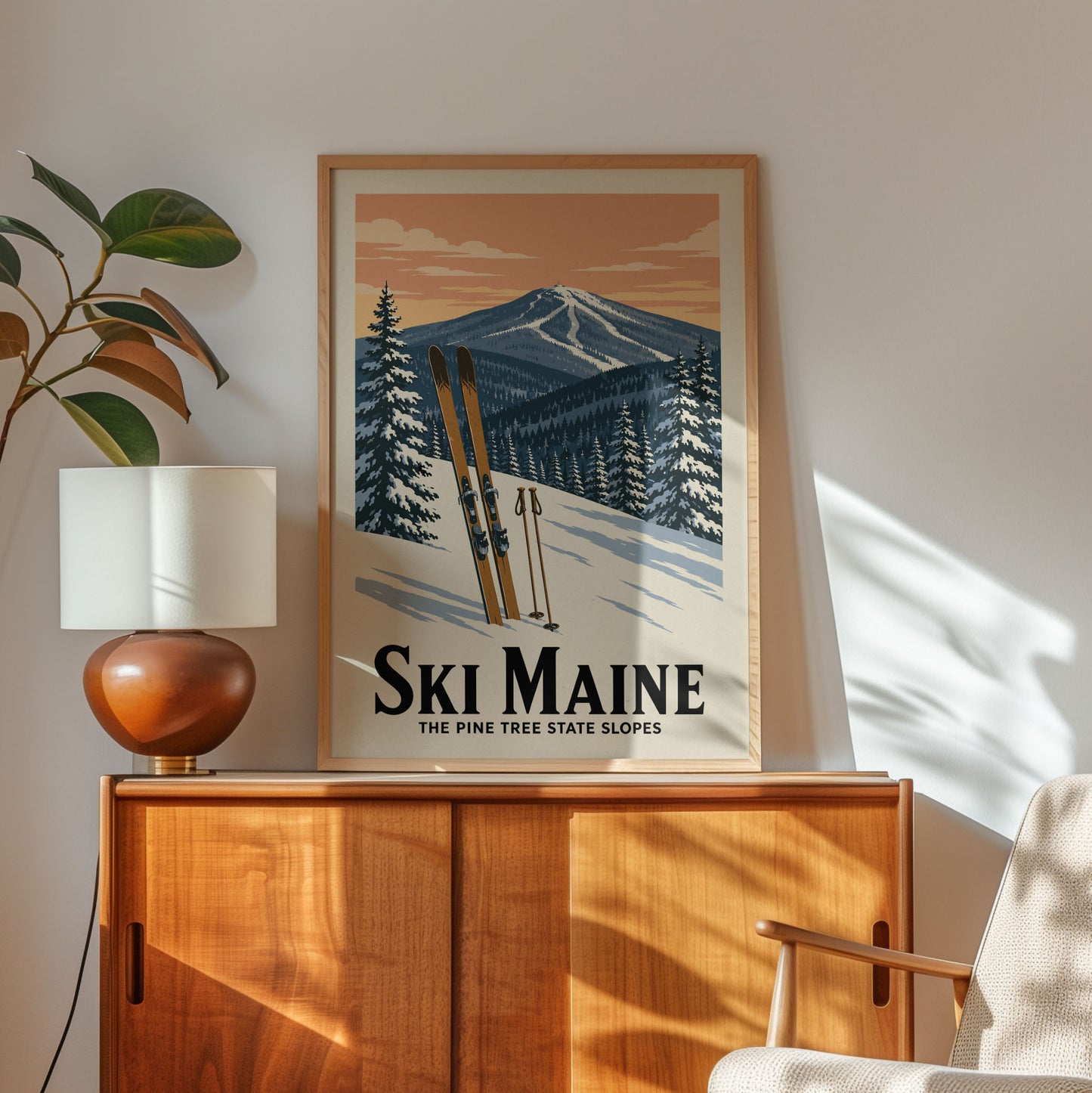 A framed poster of a snowy mountain landscape with skis is displayed on a wooden cabinet, accompanied by a lamp and a plant in the corner of the room.