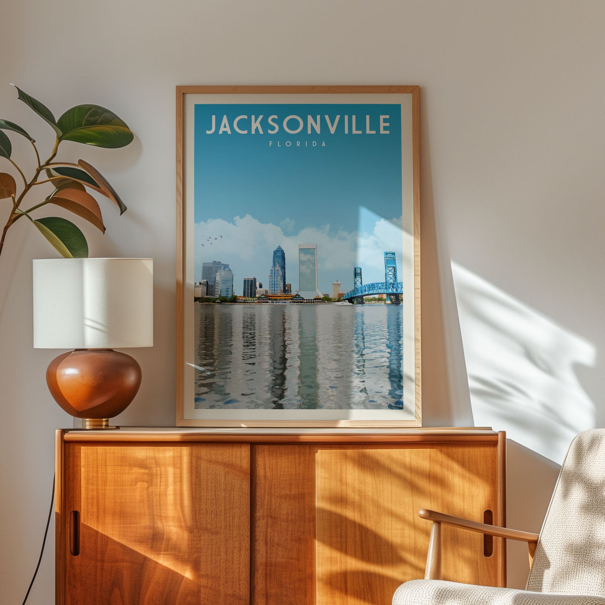 a framed poster of the Jacksonville skyline in Florida, with a wooden cabinet and a lamp in the foreground.