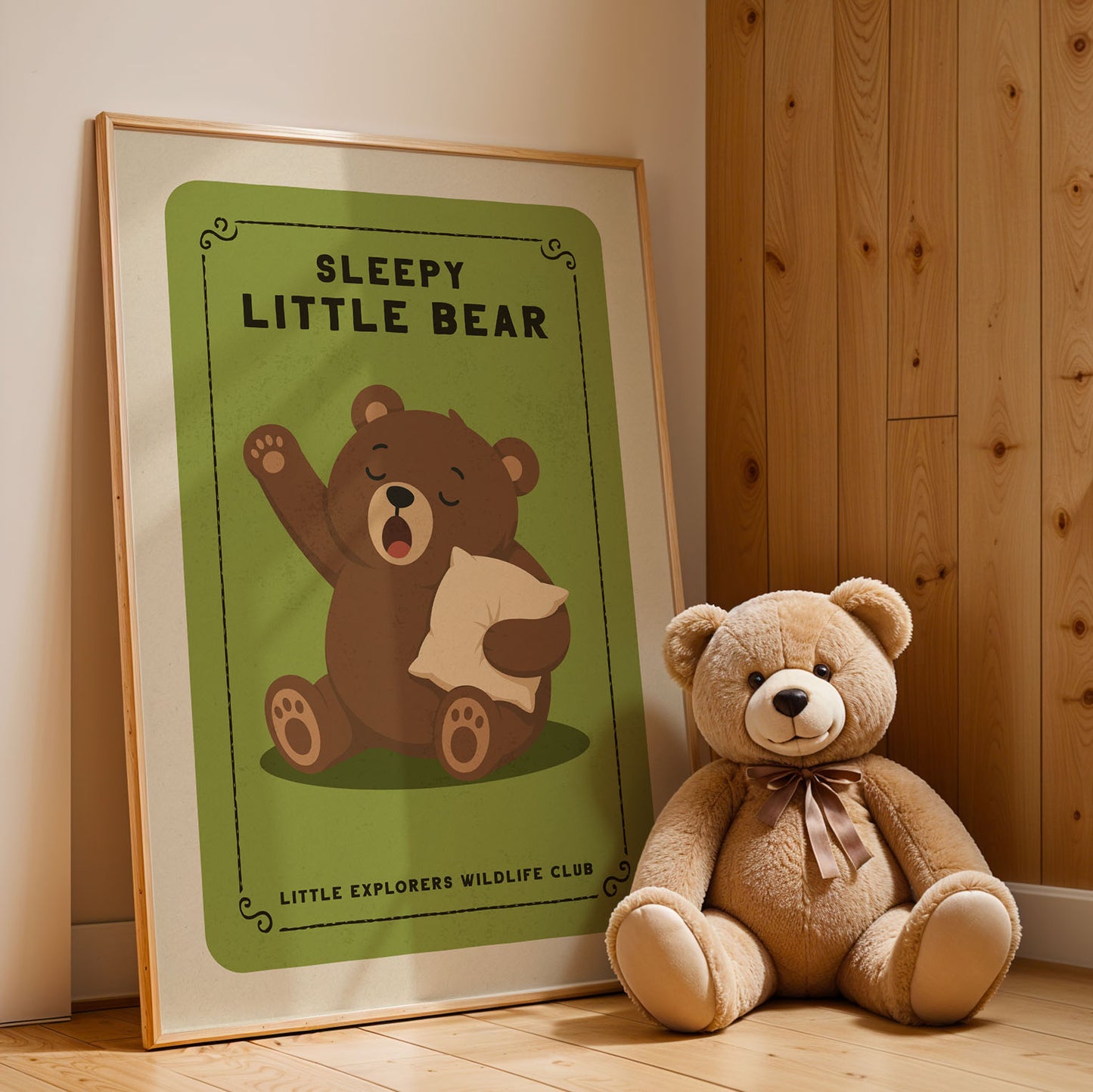 A framed poster of a sleeping bear next to a stuffed teddy bear on a wooden floor.
