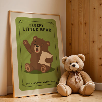 A framed poster of a sleeping bear next to a stuffed teddy bear on a wooden floor.