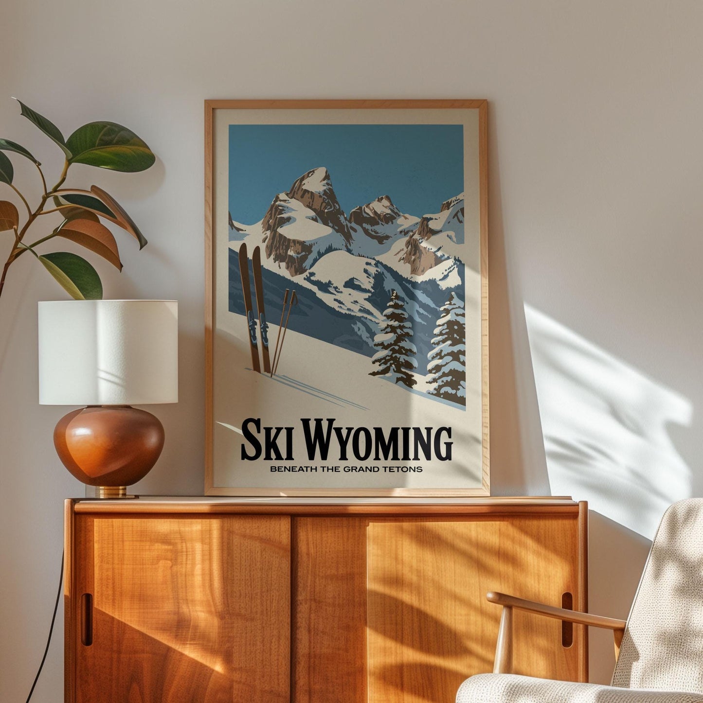 A framed poster of a snowy mountain landscape with skis is displayed on a wooden cabinet, accompanied by a lamp and a plant in the corner of the room.