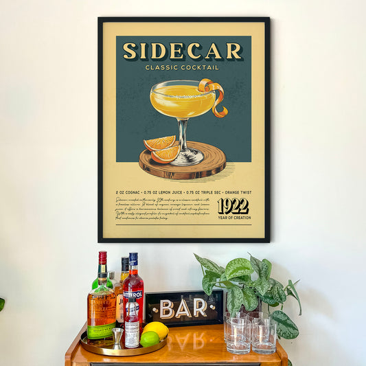 a framed poster of a classic cocktail called "Sidecar" hanging on a wall above a wooden bar counter with various liquor bottles and glasses.